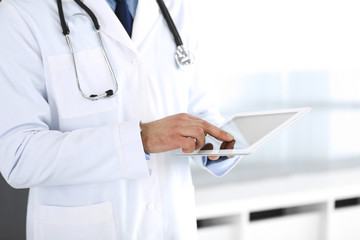 Doctor man using tablet computer for network research or virtual disease treatment, hands close-up. Perfect medical service in clinic. Modern medicine, medic data and healthcare concepts. Toned