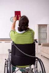 Young male invalid in wheel-chair suffering at home