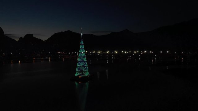 Changing light design of the floating Christmas tree in the middle of the city lake of Rio de Janeiro during sunset with diverse colour scheme