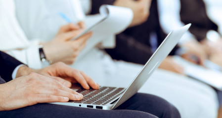 Business people working at meeting or conference, close-up of hands. Group of unknown businessmen and women in modern white office. Teamwork or coaching concept