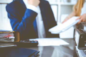 Binders with papers waiting to be processed with businessman or bookkeeper back in blur. Accounting planning budget. Audit, insurance and business concept