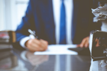 Binders with papers waiting to be processed with businessman or bookkeeper back in blur. Accounting...