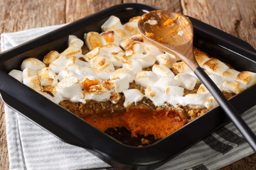 Tasty sweet potato casserole with nuts topped with marshmallows close-up in a baking dish. horizontal