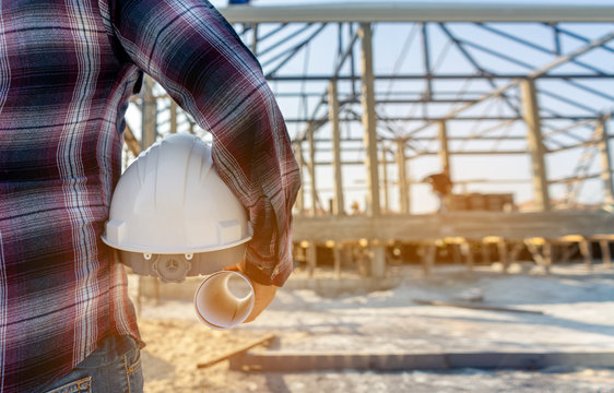 Foreman holding drawing project and holding safety helmet and looking forward to home project background concept construction working in the construction site.