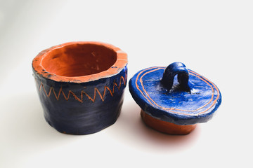 Blue with orange terracotta stripes and zigzags handmade ceramic pot with a lid on a white...