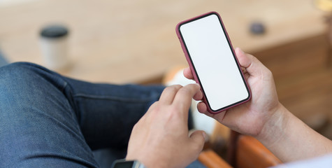 Cropped shot of man holding blank screen smartphone while sitting in comfortable workplace