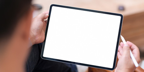 Close-up view of man using blank screen tablet in comfortable room