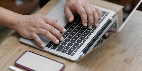 Cropped shot of man working on his project while typing on laptop computer