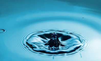 Closeup Water drop falling on the surface of the water and beautiful circular wave ripple, fresh natural mineral water drink water concept