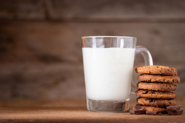 Chocolate chips cookies with crumbs and fresh milk on wooden background, homemade sweet and dessert concept