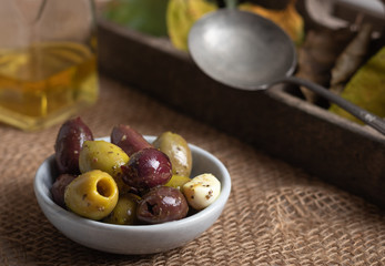 Black and green olives in a small bowl on a autumn background