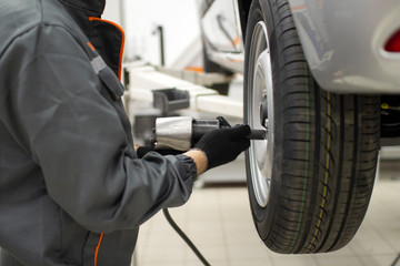 Tire service. Mechanic attaches the wheel to the car