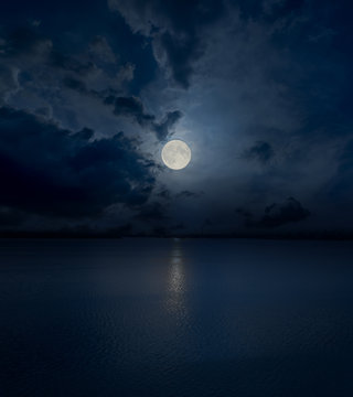 full moon in clouds over water