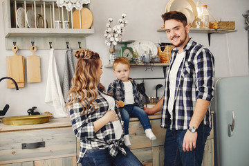 Family on the kitchen. Blonde in a blue shirt. Pregnant woman with her husband and little son