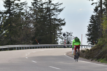 Schwarzwald, Germany - April 25 2019: Highway through the forest and a cyclist in a green jacket with a backpack and helmet