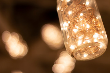 Jars hanging from the ceiling of the bar with warm led lights inside.