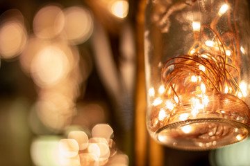 Hanging jars with warm led lights inside and some bokeh in background.