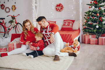 Obraz na płótnie Canvas Beautiful family sitting at home. Cute mother in a red sweater. Little boy with handsome father