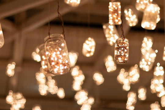 Jars hanging from the ceiling of the bar with warm led lights inside.