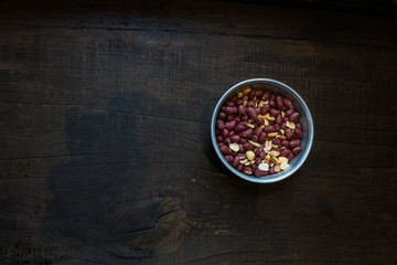 Top view of Roasted peanuts in an iron bowl on dark brown wooden.