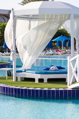 Naklejka premium A romantic place by the pool, decorated with white curtains floating in the wind.