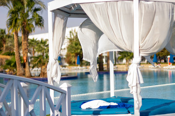 A romantic place by the pool, decorated with white curtains floating in the wind.
