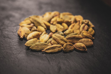 Heap fo green cardamom seeds in black slate background. Close up view. 