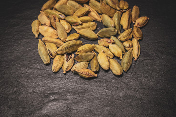 Heap fo green cardamom seeds in black slate background. Close up view. 