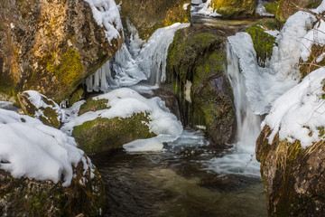 vereister wildbach mit eis und felsen
