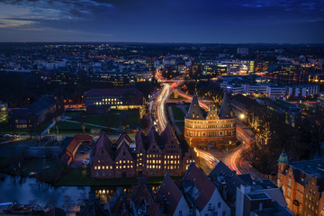 Aerial night view of the illuminated city of Luebeck, Germany in winter with Holstentor and...