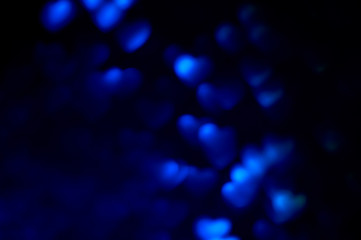 Blue space blurred three-dimensional heart-shaped bokeh on black and dark blue background , neon juicy bright colors, Valentine's day, holiday card, abstract background