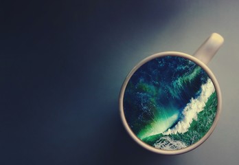 White cup with water. Sea. Ocean. Sea waves. Creative postcard.