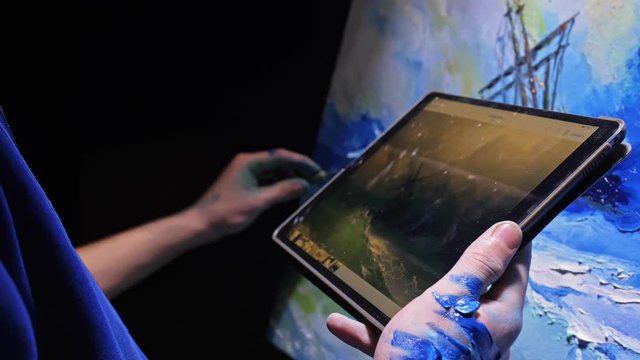 Artist copyist paint seascape with ship in ocean. Craftsman decorator draw as boat sail on blue sea with acrylic oil color. Draw finger, brush, knife palette. Indoor. In hands of tablet computer pc.