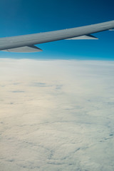 At sunrise wing of an airplane flying above the clouds in winter