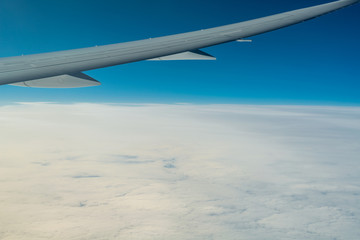 At sunrise wing of an airplane flying above the clouds