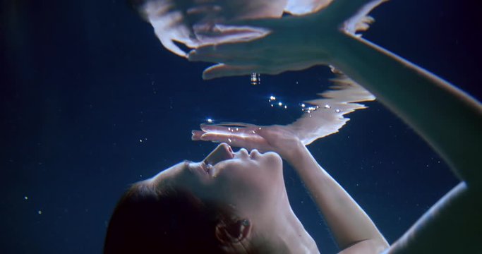 beautiful girl touches surface diving underwater slow motion