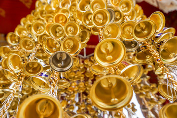Look up view of of many small golden bells was hung in a group in Thai temple. Thai texts in an image is mean Wish ( in English )