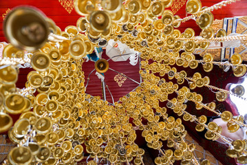 Look up view of of many small golden bells was hung in a group in Thai temple. Thai texts in an image is mean Wish ( in English )