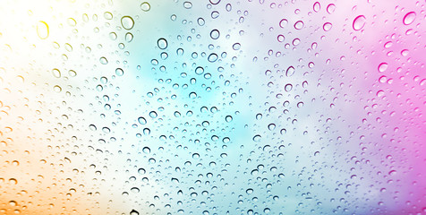 Closeup raindrops on glass and blurry colorful background.