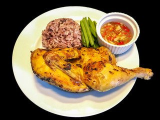 close up of Kai yang in Thai or chicken grilled with spices and herbs served with brown sticky rice and chili sauce with green vegetable, black background with clipping path.   