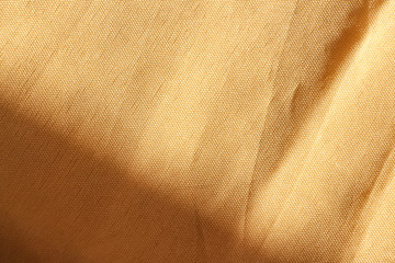 Light yellow silk fabric. Textile Background Texture. Expensive material. High resolution. Bruises are visible on the surface of the fabric. Shade falls on textiles.