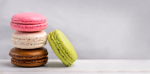 Retro pastel colorful macaroon cookies on vintage background with copyspace. Homemade french macaron dessert with different flavors: chocolate, strawberry, vanilla, pistachi