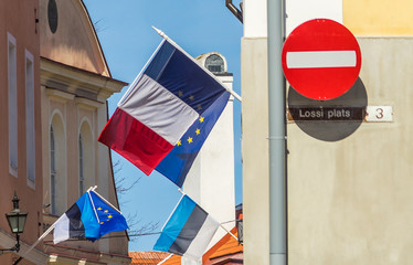 20 April 2018 Tallinn, Estonia. Flags of France, Estonia, the European Union and a Stop sign on the building against the blue sky on a bright Sunny day