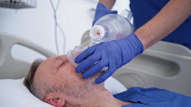 Defibrillation.Doctors save patient's life in clinic. Nurse and a specialist give resuscitation to a male patient in the emergency room. Cardiac massage.