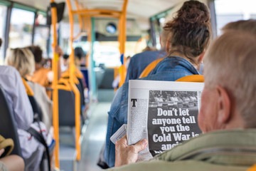 Alter Mann ließt im Bus Zeitung über Krieg
