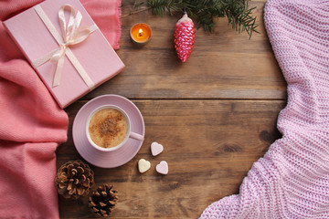 cappuccino with cinnamon in a pink cup, a gift in a box, sweets, candles, cones, Christmas decorations, plaid on an old wooden table, top view, flat, concept cozy home, christmas, copy space