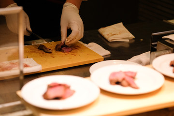 Obraz na płótnie Canvas Close up chef hands in gloves slicing piece of beef steak
