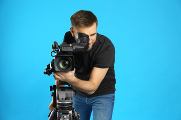 Operator with professional video camera on blue background