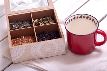 assortment of dry tea in a box for tea and a mug on a light background