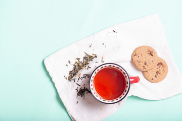 brewed black tea in a mug on a cotton napkin with cookies on a light background, top view